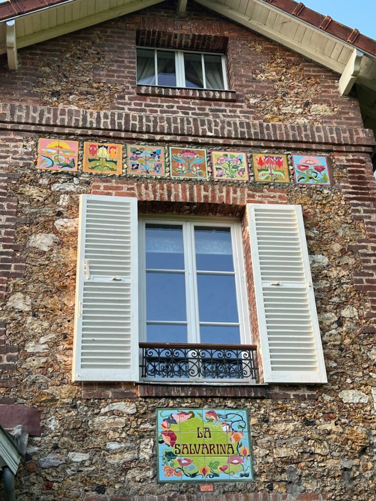 Carreaux de céramique fleuris alignés sur façade en briques – La Savarina, par Laurence Brecher