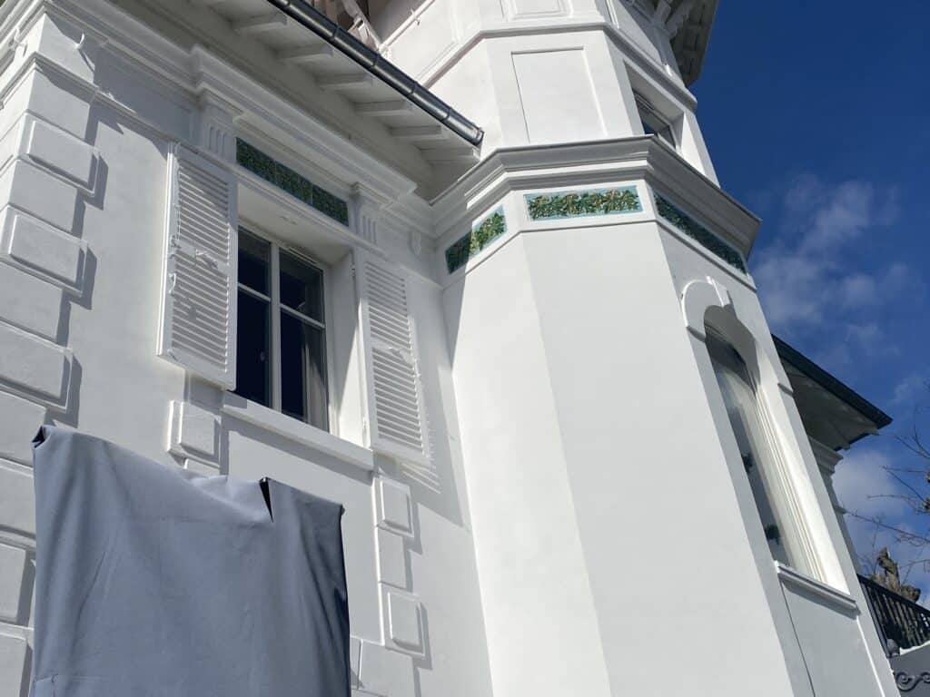 Frises en céramique bas-relief intégrées à la façade d'une villa blanche au Vésinet