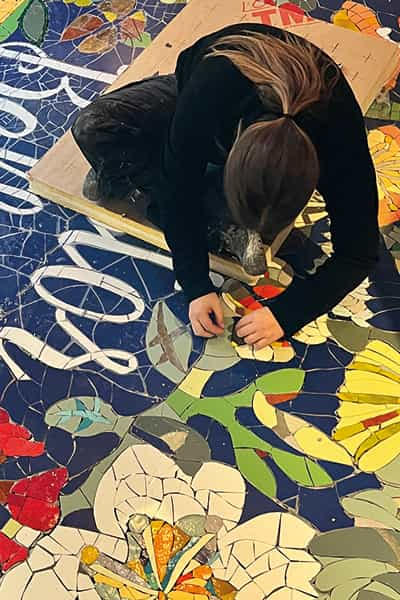 Artisan mosaïste posant la mosaïque de sol Castor Bellux à Dinard, entreprise Salmon Carrelage, pose morceau par morceau