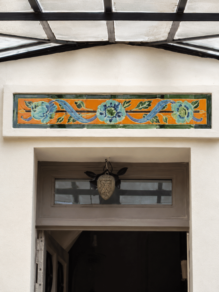Frise en céramique murale au-dessus d'une porte d'entrée à Colombes, motif floral Art Nouveau